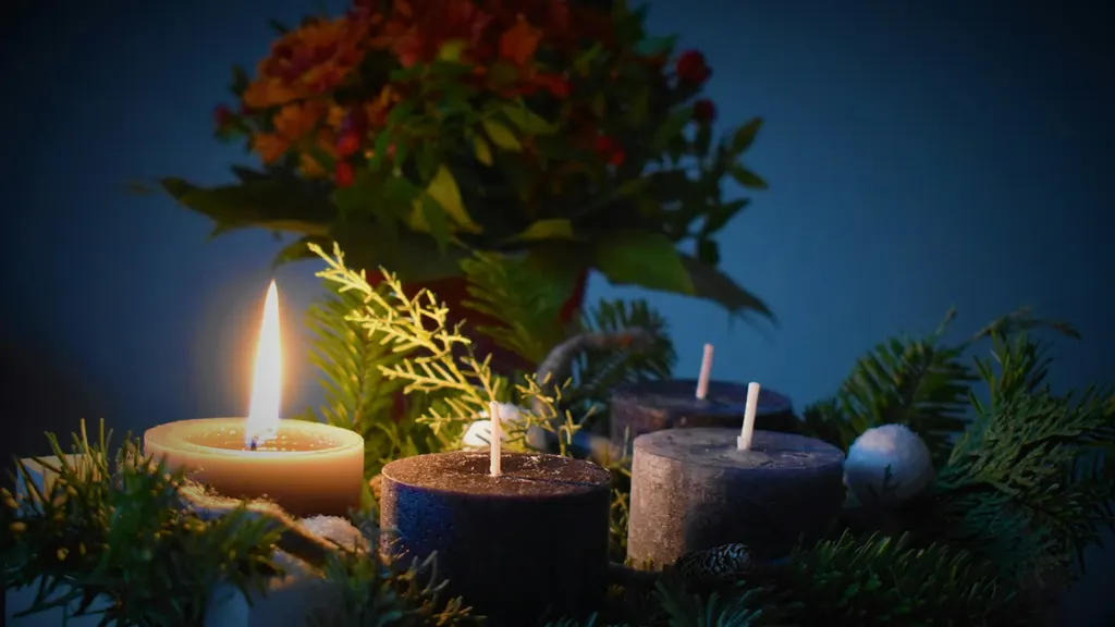 An Advent wreath of evergreen branches with the first of four candles lit, the other three still unlit